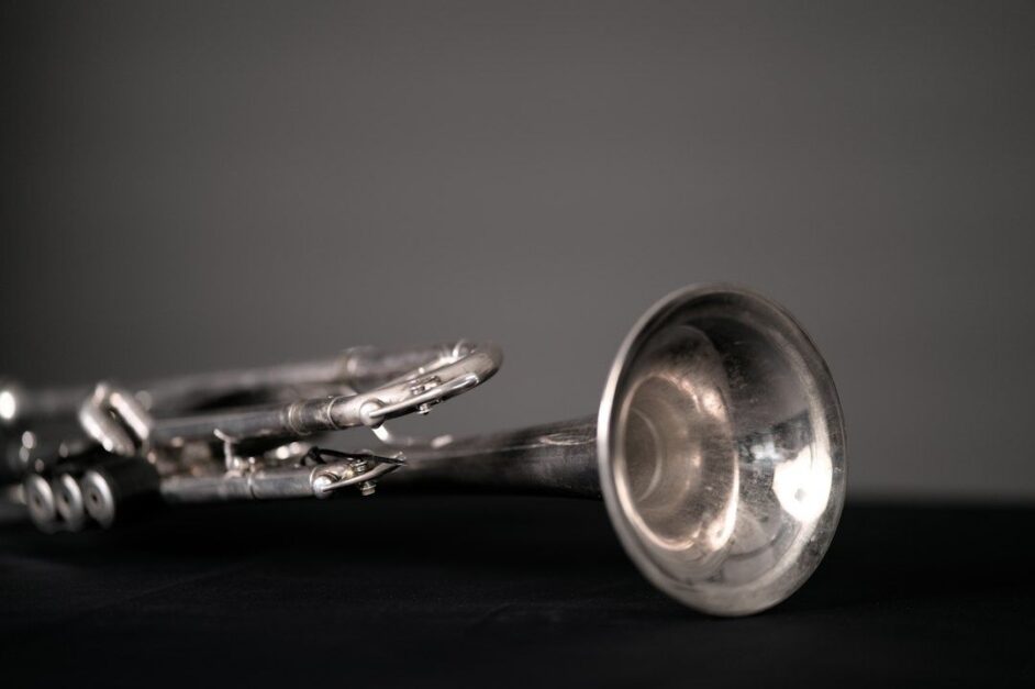 Närbild av en sliten trumpet liggande på ett mörkt underlag